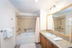 The guest bathroom has an oversized vanity, bathtub & laundry area.